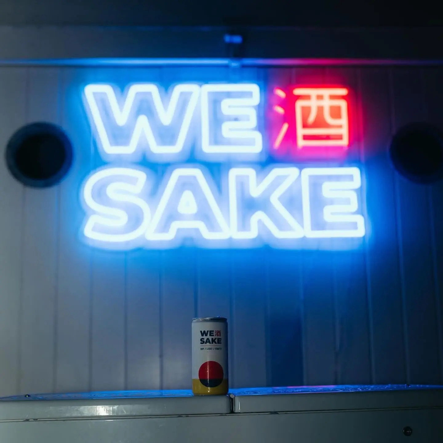The neon WESAKE sign over a bar with a can
