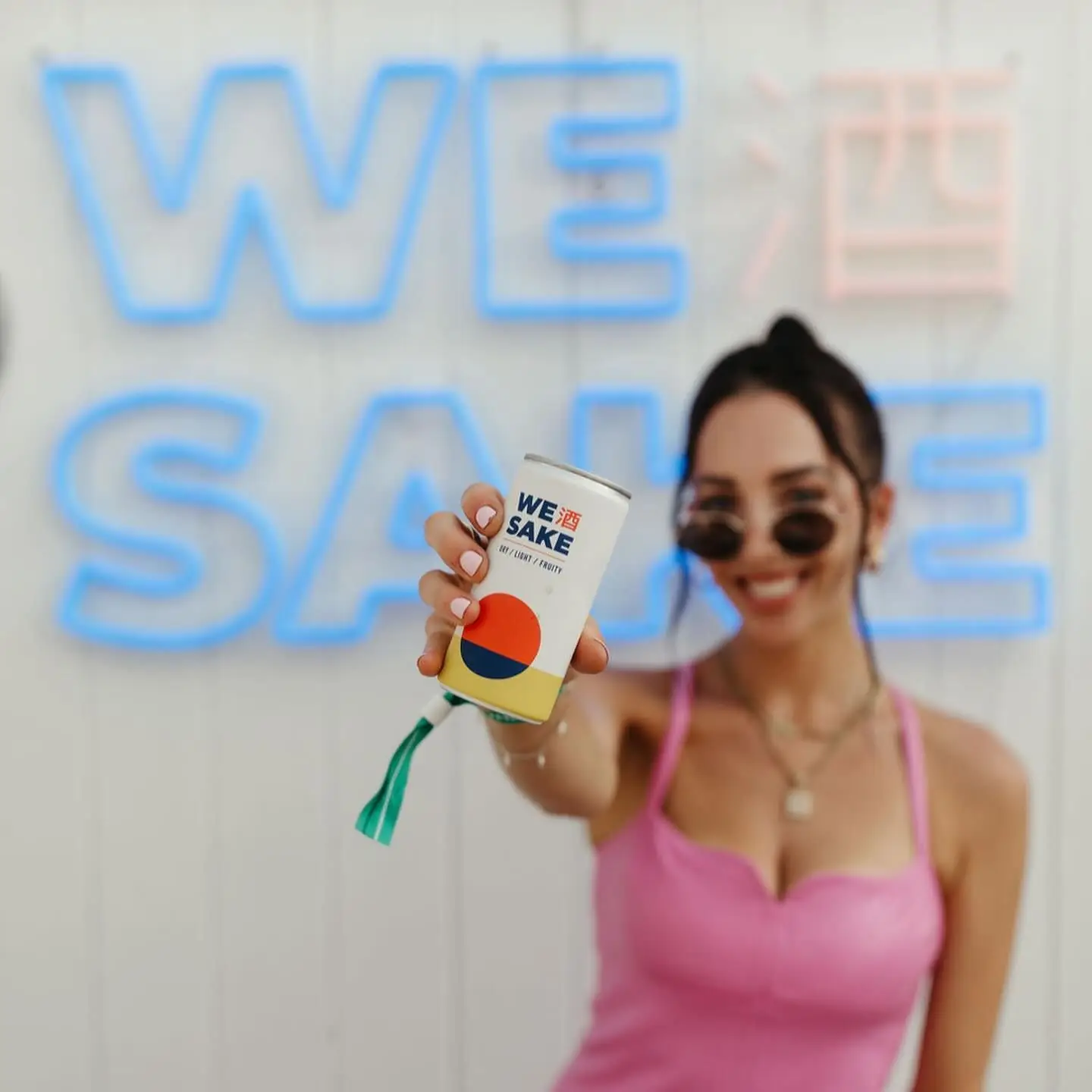 Holding up a WESAKE can in front of the neon WESAKE sign