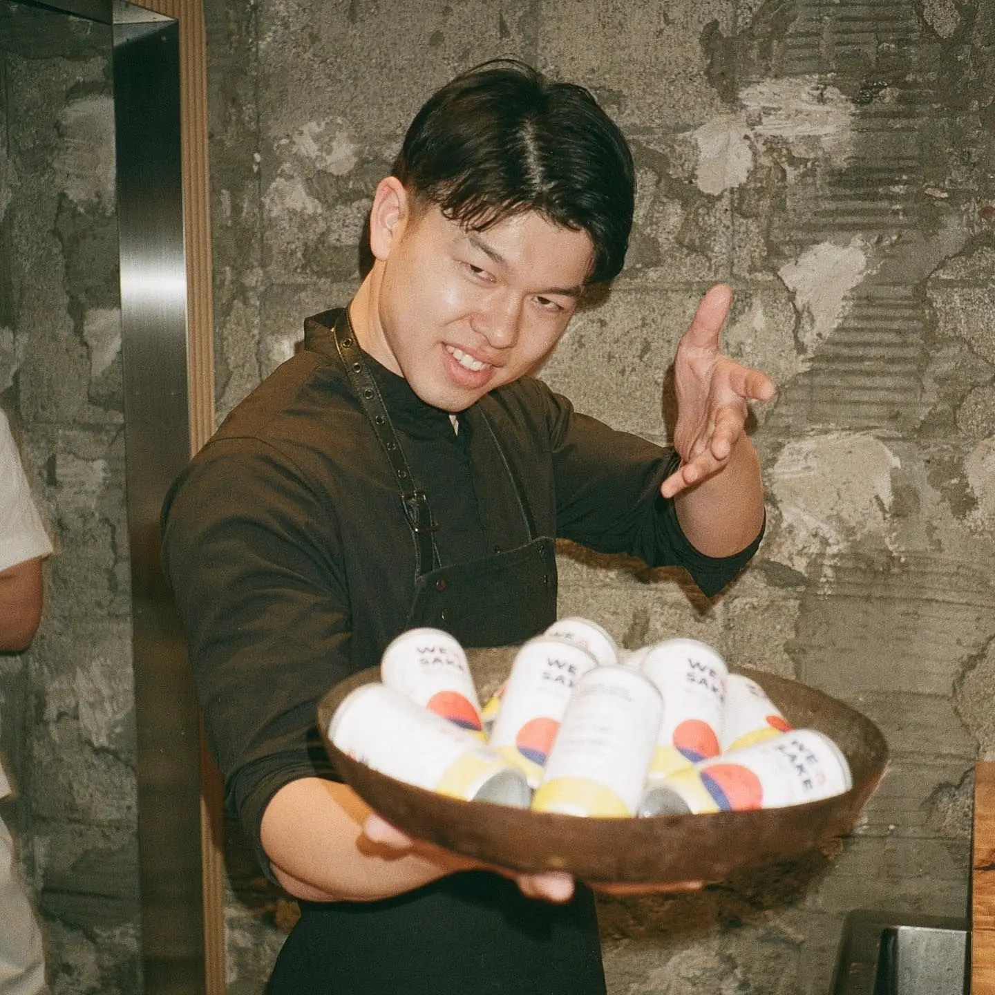 A chef holding a bowl of WESAKE cans
