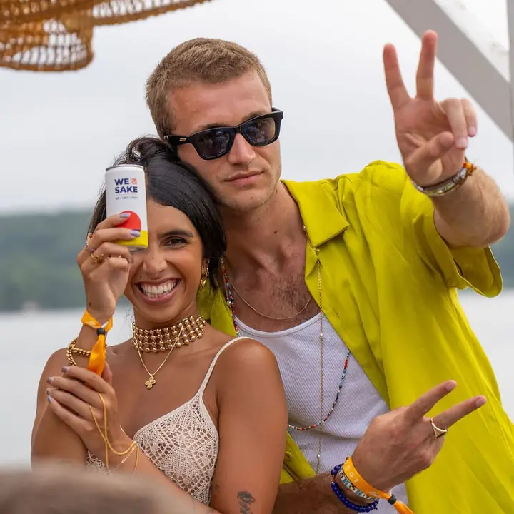 Friends holding up WESAKE cans at The Surf Lodge